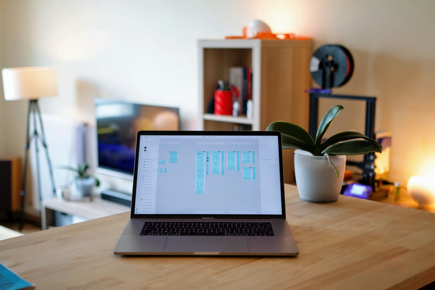 Laptop displaying user interface design application on a wooden desk.